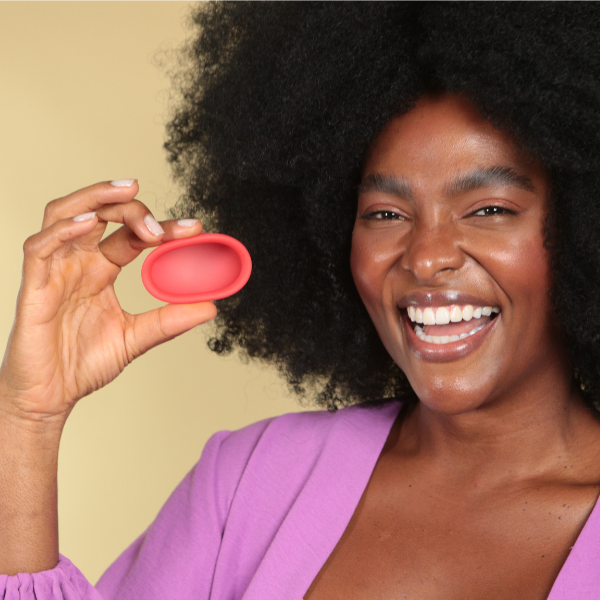 Mulher sorrindo segurando um disco menstrual